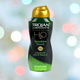 A bottle of Trojan H2O Sensitive Touch with Aloe Lubricant sits against a blurred multi-colored backdrop. The 5.5 fl oz bottle, perfect for sensitive skin, is infused with Aloe & Vitamin E, offering a moisturizing lubricant experience.